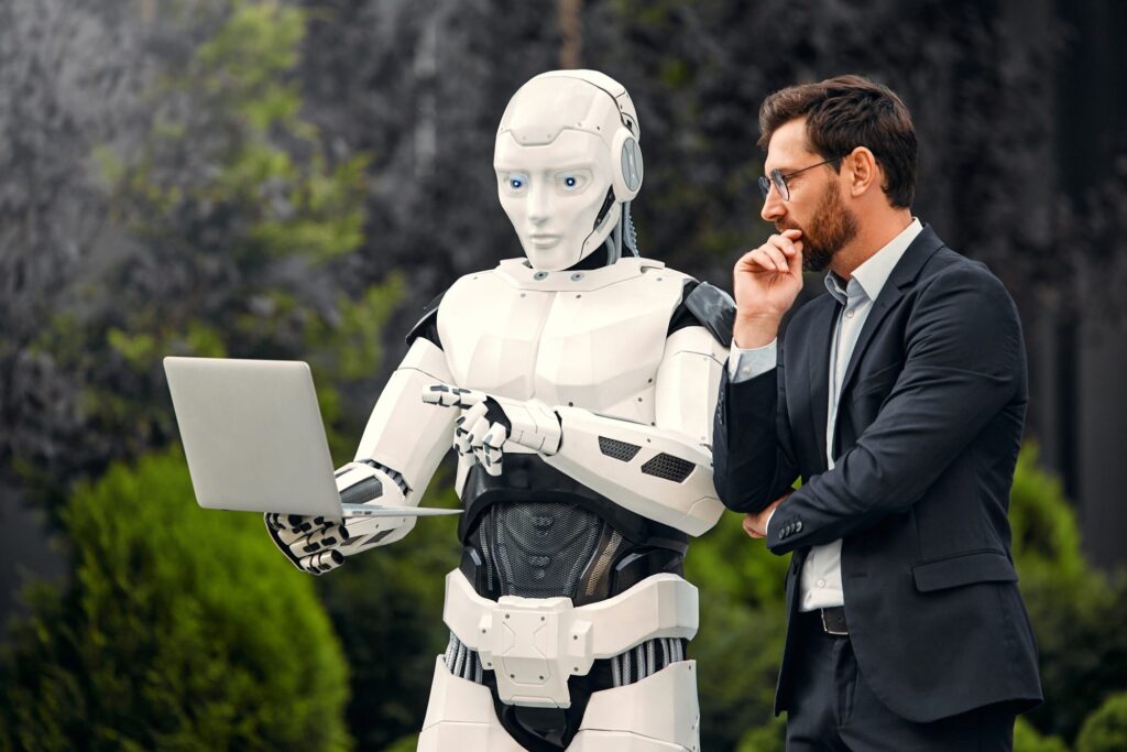 Robot humanoidalny i biznesmen analizują dane na laptopie