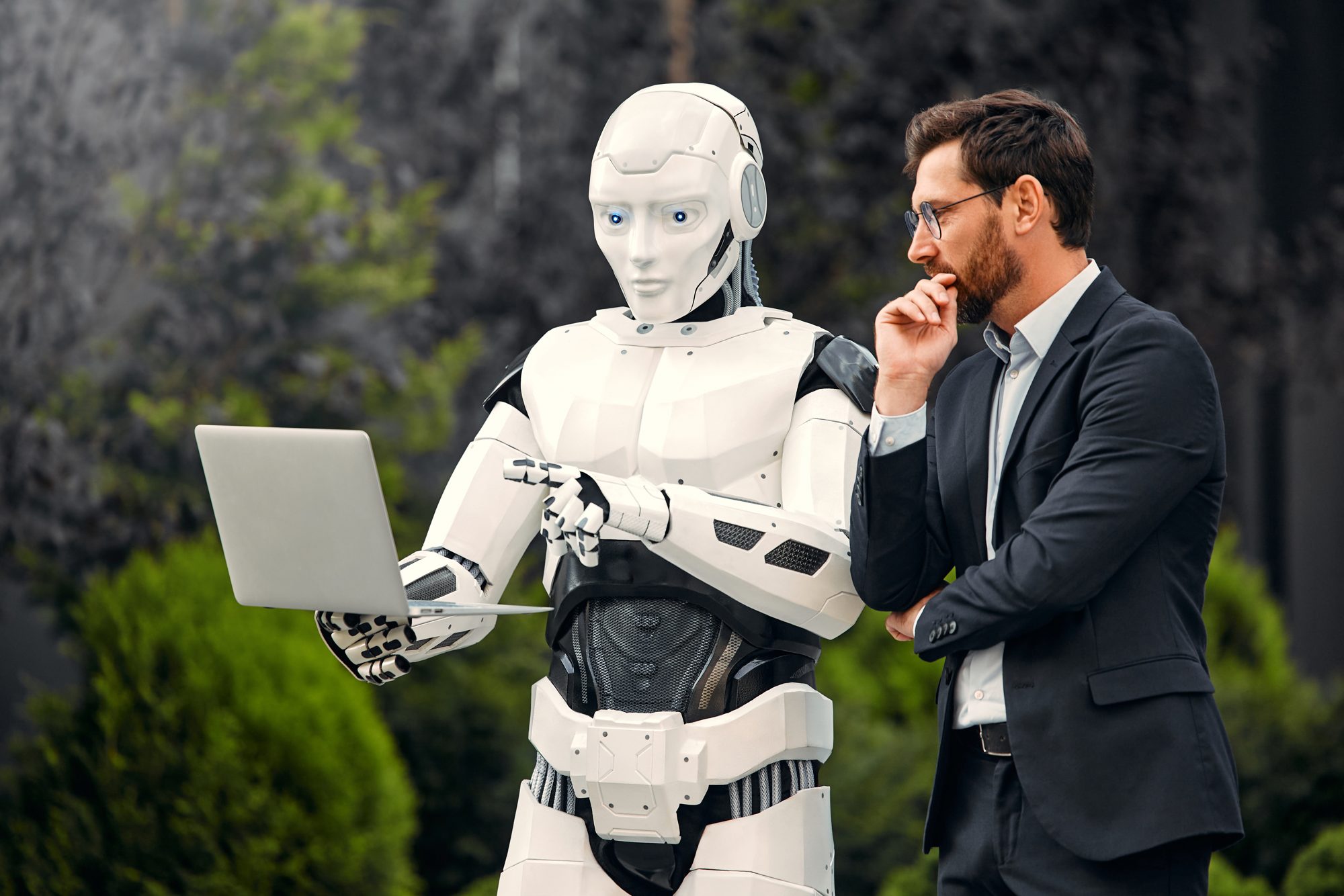 Robot humanoidalny i biznesmen analizują dane na laptopie